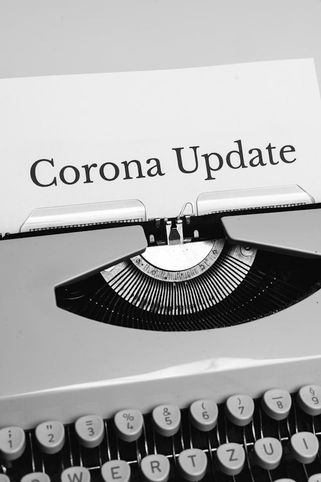 Black and white photo of a typewriter with 'Corona Update' paper, reflecting news and communication.