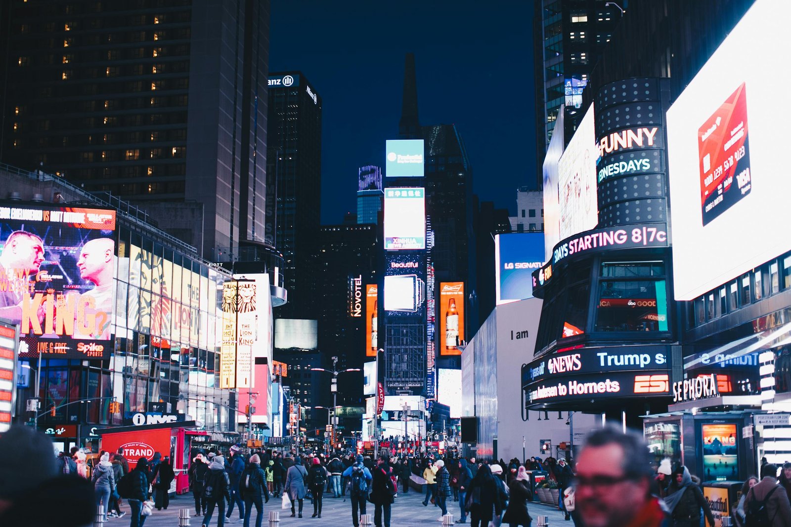 Bustling night scene in Times Square, New York City, illuminated with vibrant advertisements.