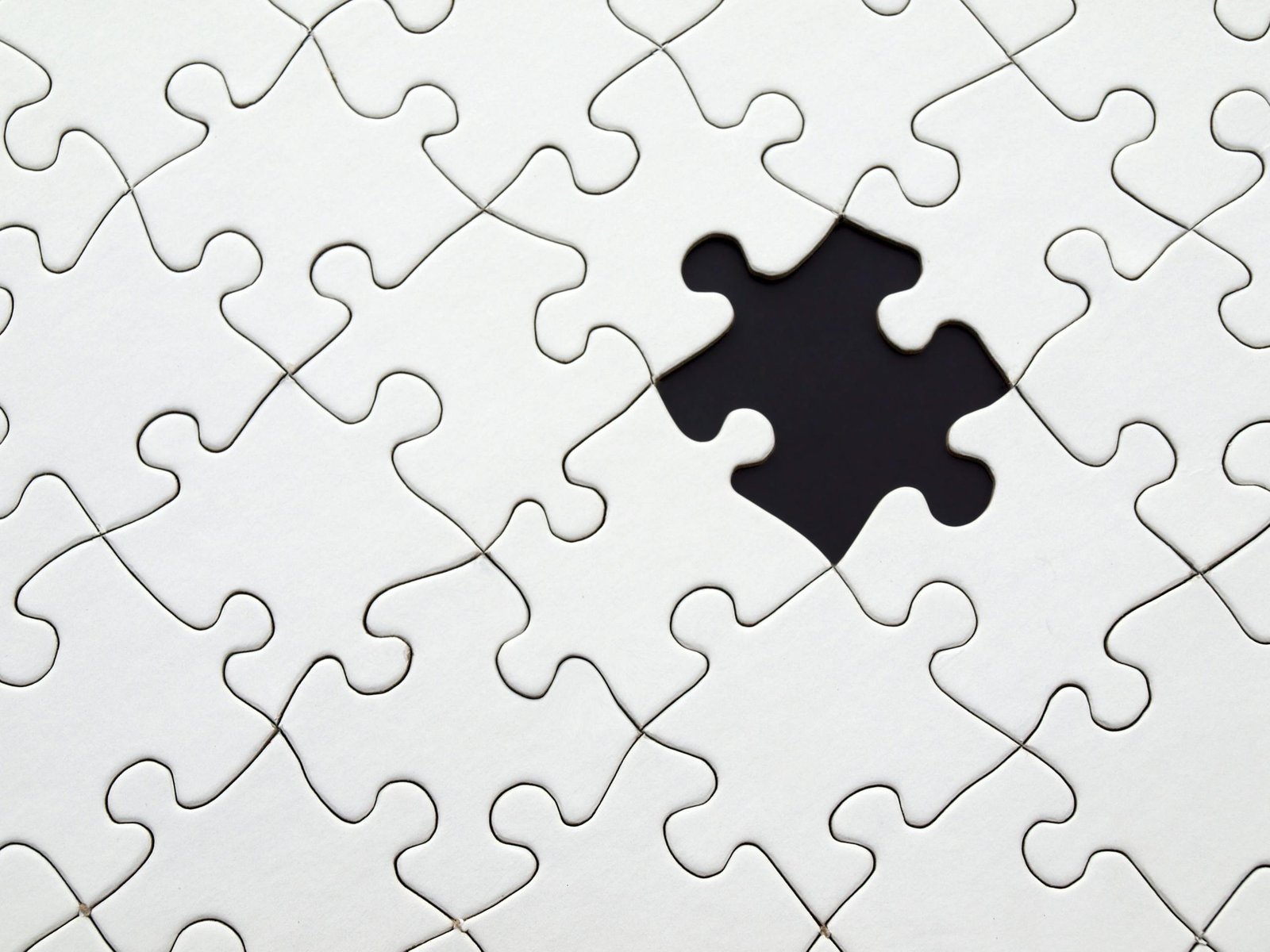 Close-up of an incomplete white puzzle with one missing piece, symbolizing challenge and strategy.